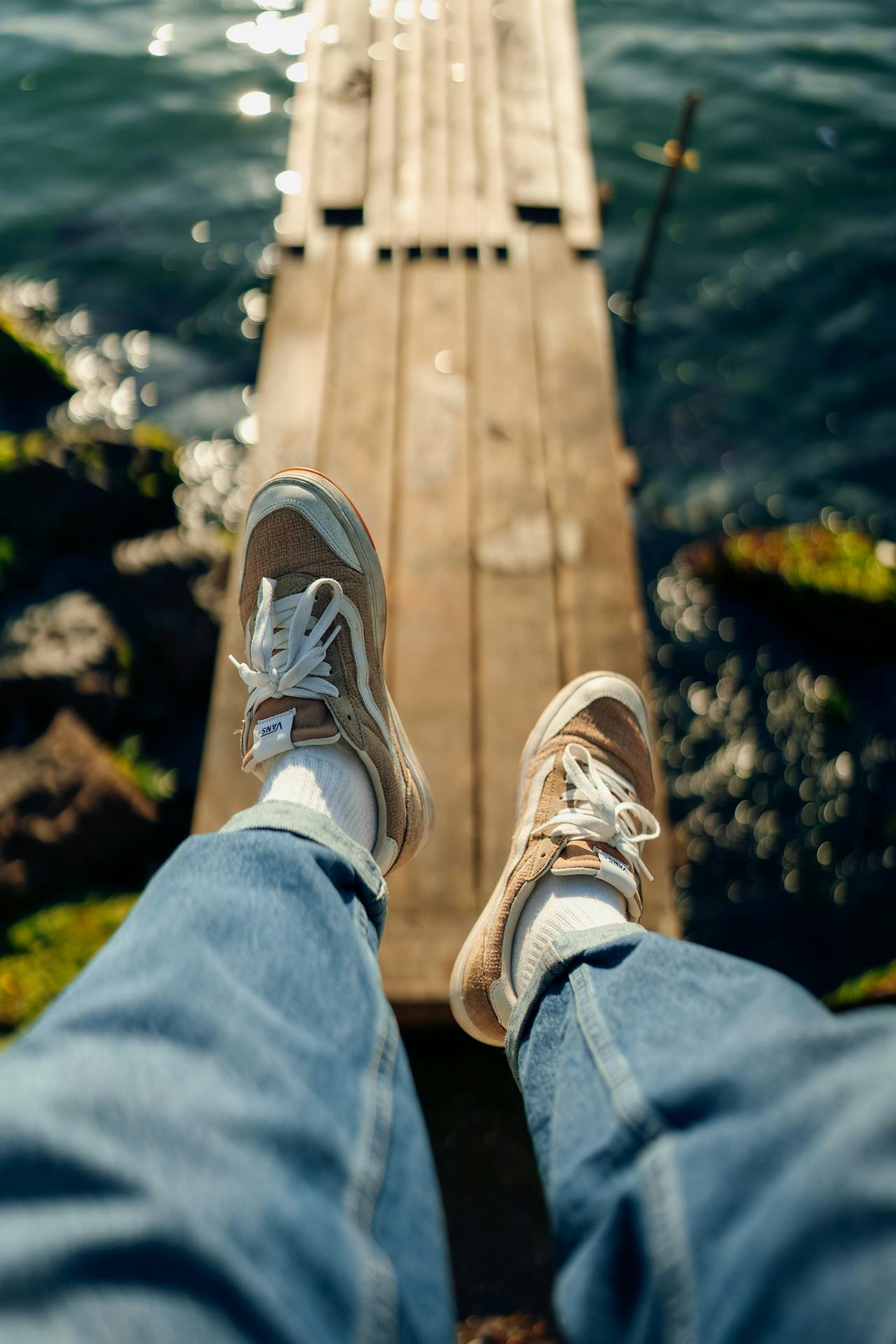 An image of two legs dangling over water wearing Vans shoes to represent an introvert lifestyle